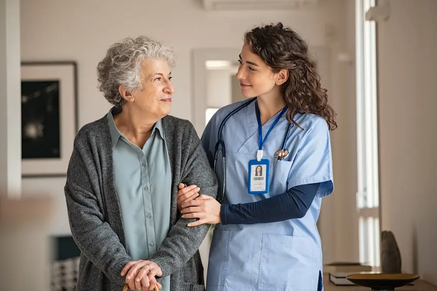 Nurse walking arm in arm with an older woman at home