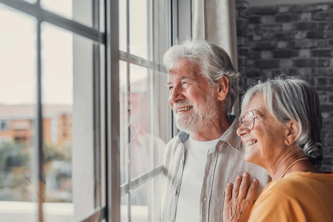 Smiling older couple looking out of a window