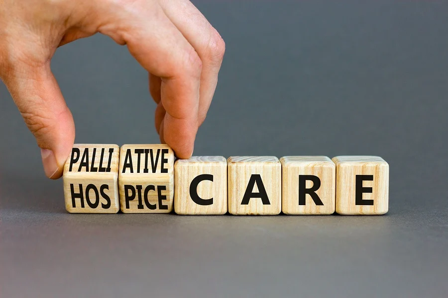 Hand placing wooden blocks to spell palliative and hospice care