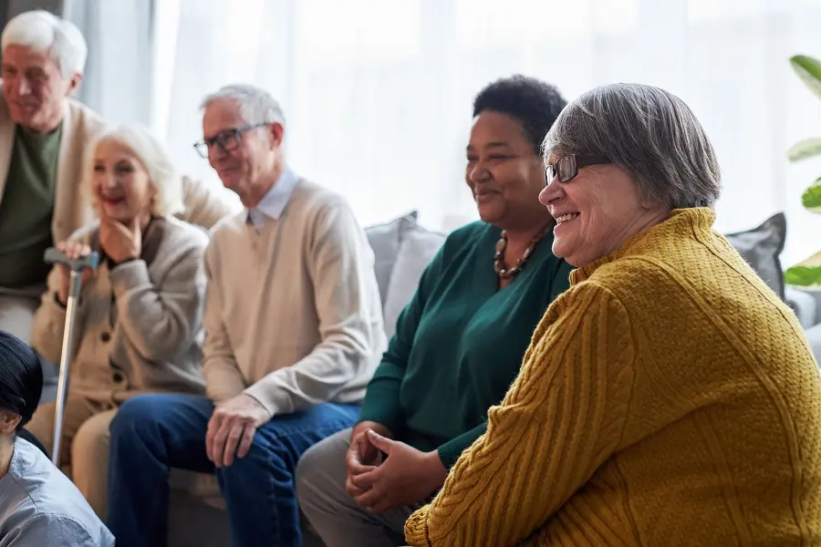 Group of older adults talking together in a bright living room