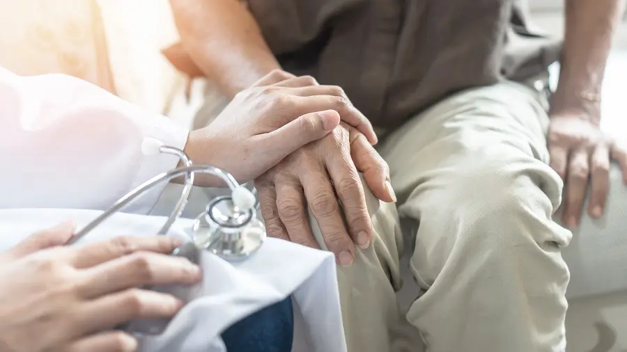 Clinician with a stethoscope holding a patient's hands