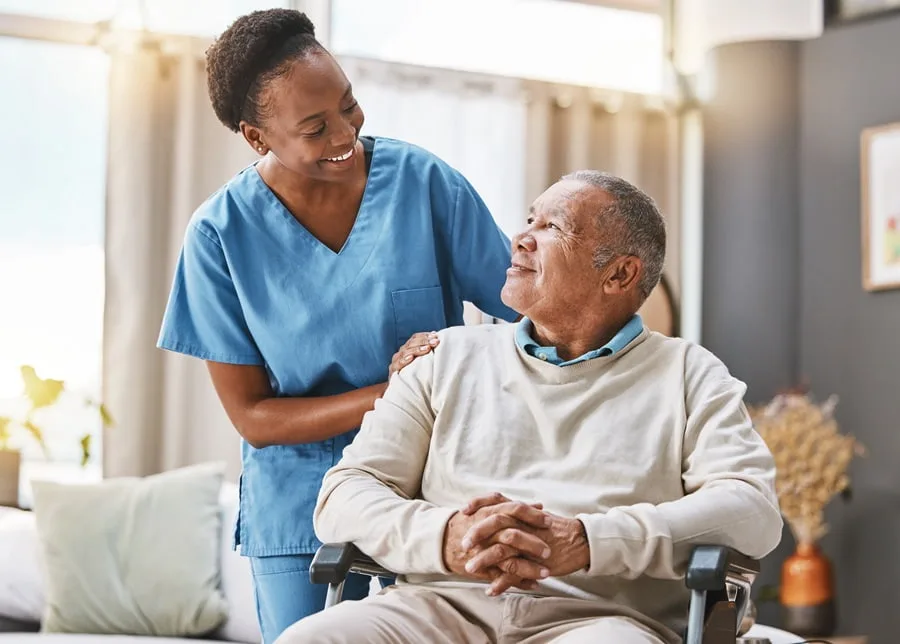 Nurse with her hands on the shoulders of a smiling older man