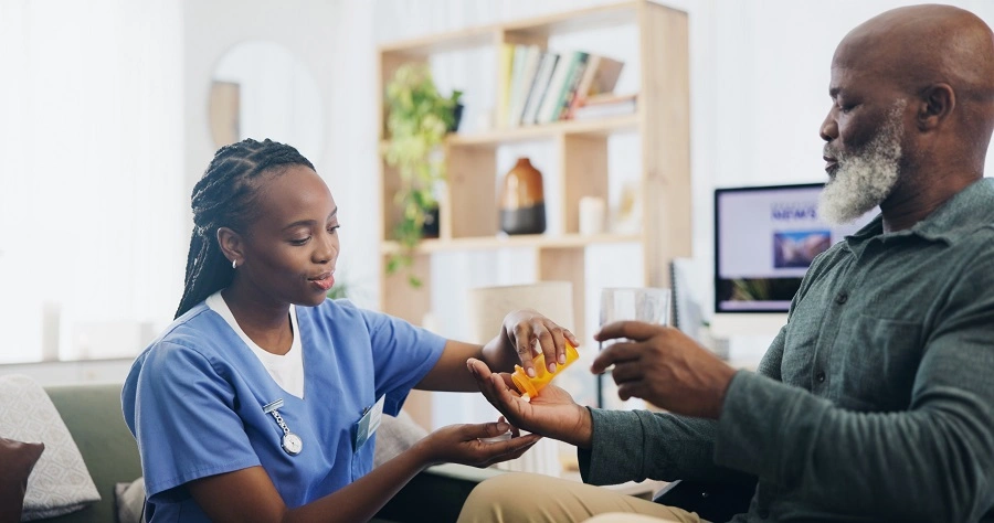 Nurse handing medication to an older man at home