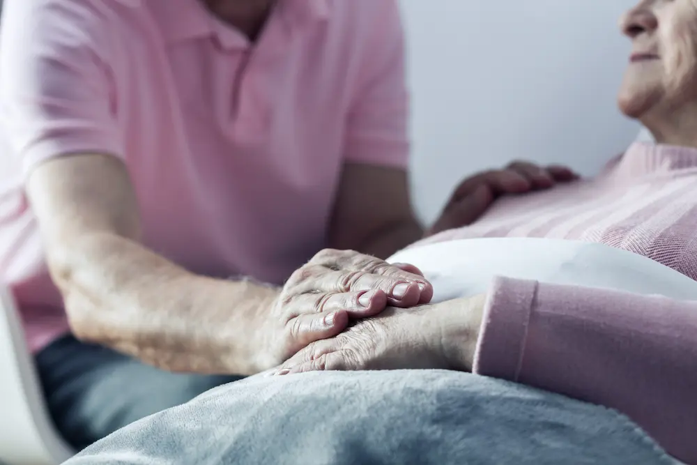 Close-up of a caregiver's hand on an older person's hands