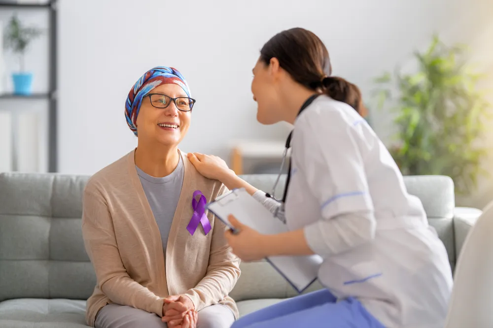 Nurse talking with a smiling older woman wearing a head scarf