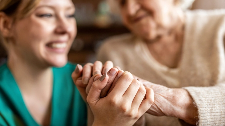Young caregiver holding an older woman's hands