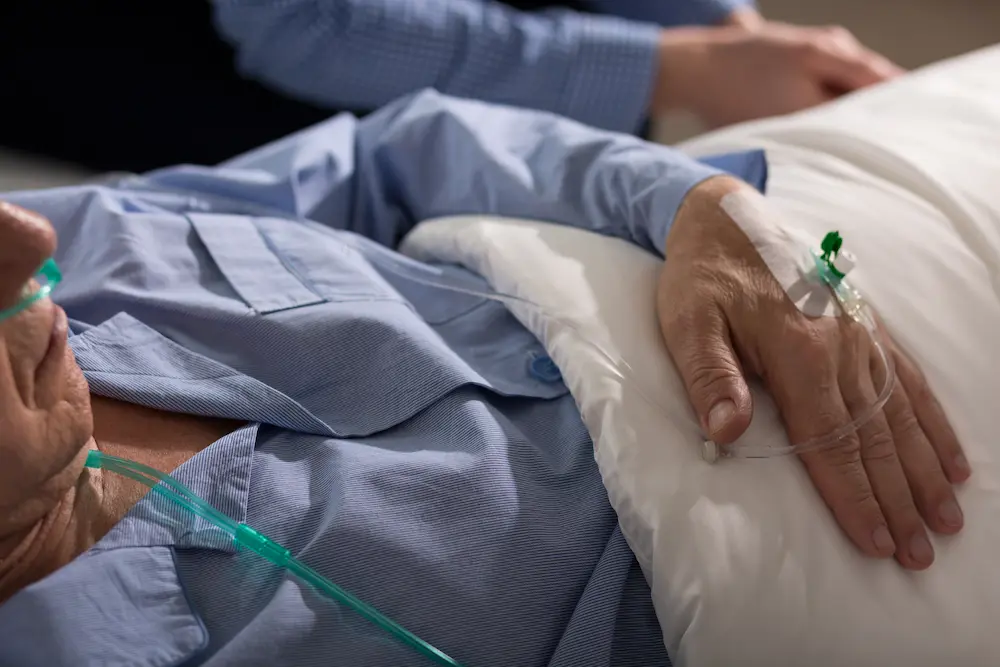 Primer plano de un paciente en la cama con una vía intravenosa y un tubo de oxígeno.