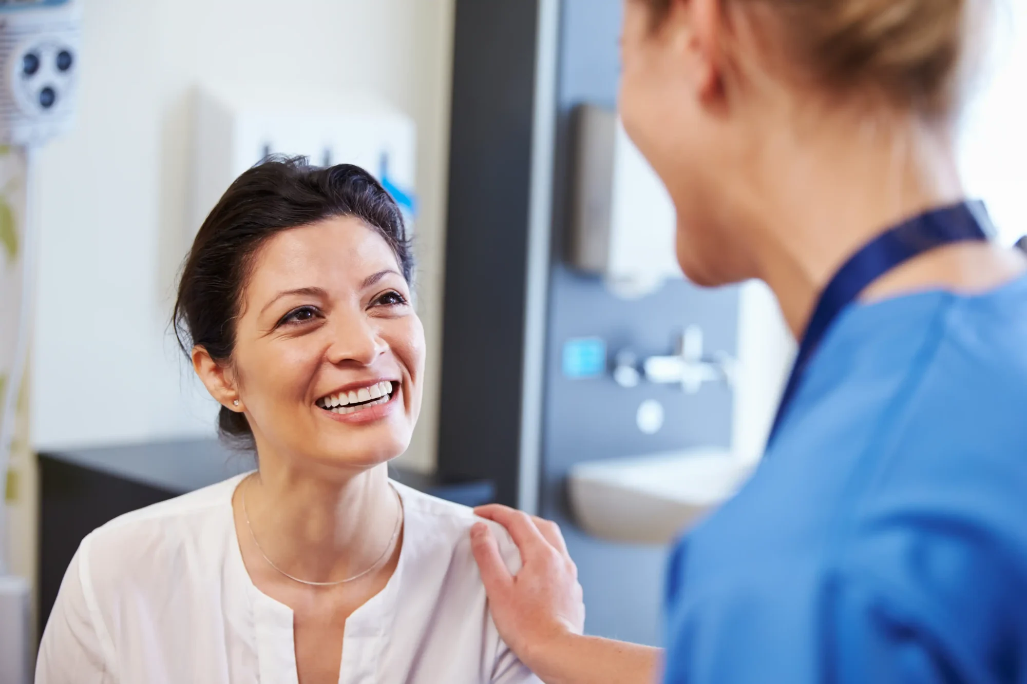 Nurse talking with a smiling woman in a clinic room