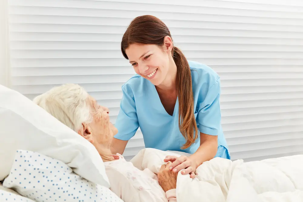 Nurse caring for an older woman resting in bed