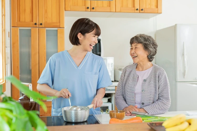 Cuidadora cocinando con una mujer mayor en su cocina.