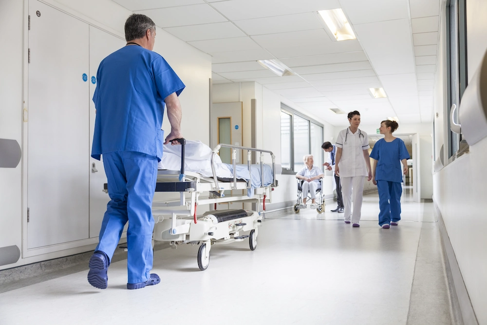 Una enfermera empuja una camilla de hospital por un pasillo.