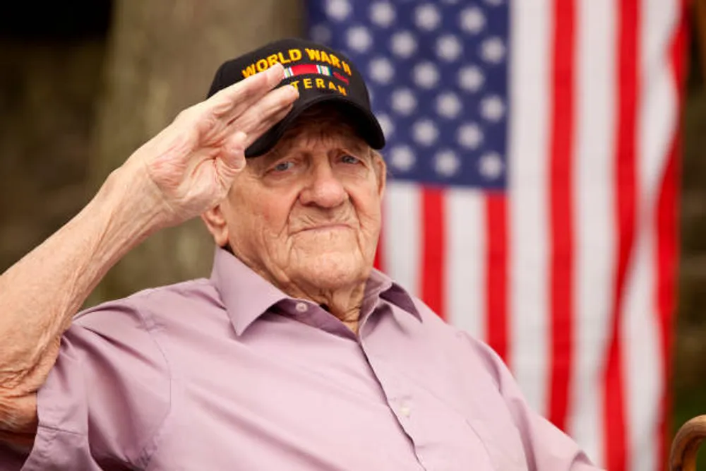 Veterano de la Segunda Guerra Mundial saludando frente a una bandera estadounidense.