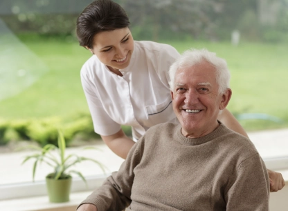 Caregiver with a smiling older man sitting outdoors