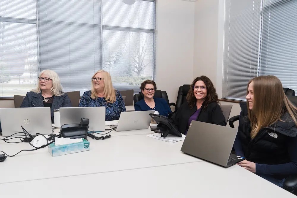 APEX interdisciplinary team meeting around a conference table with laptops