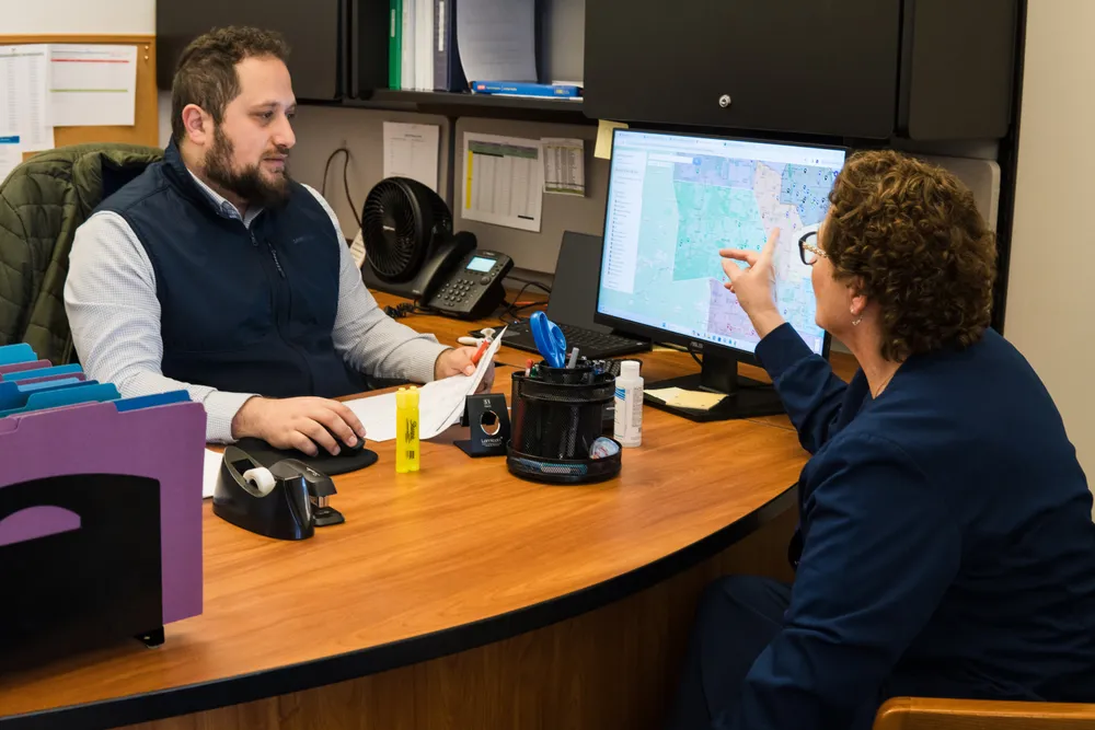 Two APEX staff members reviewing a map on a computer screen at a desk